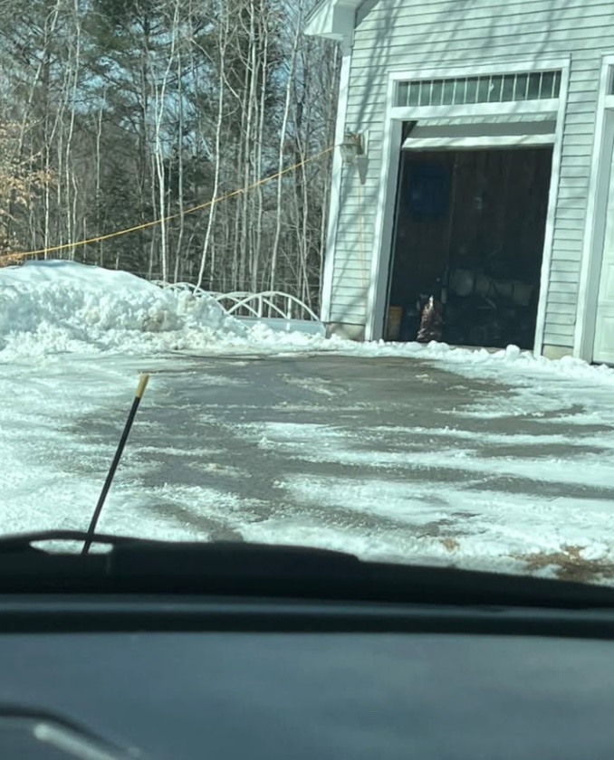 A cleared residential driveway beside a garage after snowplowing